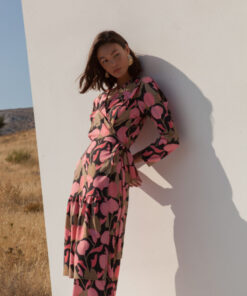 model wearing flory pink floral dress by mallory leaning on white wall