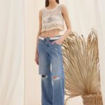 Fishnet crop top with fringes by The KNLs styled with denim jeans, full look